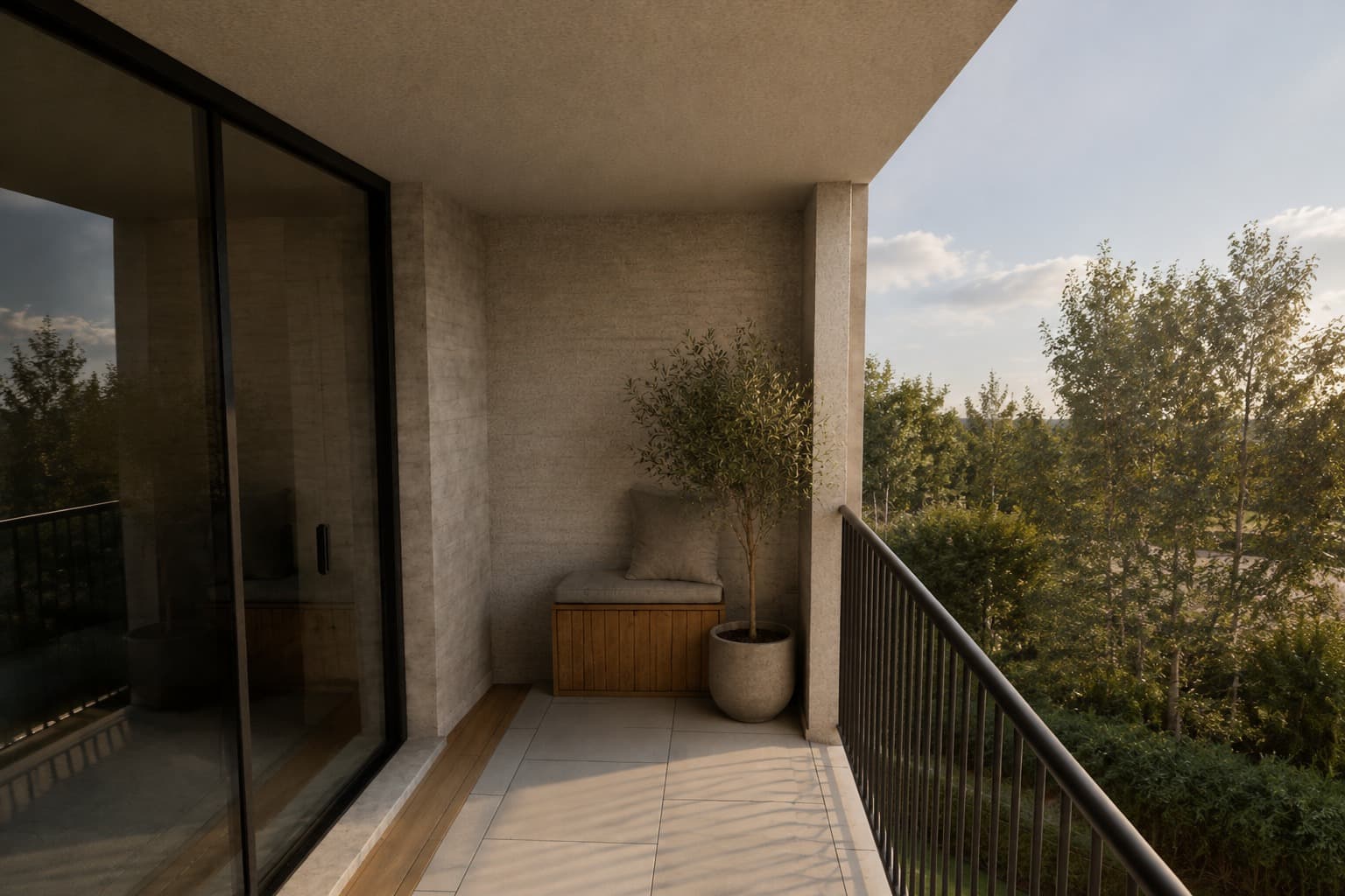 The balcony of a unit in late afternoon, with the built-in bench, the potted olive tree and the trees opposite.